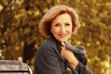 Obraz premium Gorgeous middle aged woman sitting on bench in autumn park
