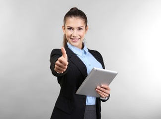 Confident young woman with tablet computer, on light background