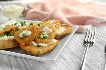 Plate with tasty potato pancakes for Hanukkah on wooden table