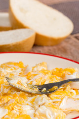 Scrambled eggs on the plate with fork and bread