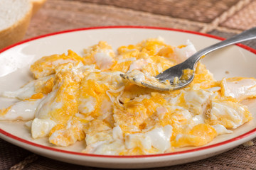 Scrambled eggs on the plate with fork