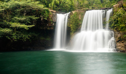 Fototapeta na wymiar Klong Chao waterfall serenely cascades into the tranquil green pool below. It is located in the interior of the island of Koh Kood, Thailand. 