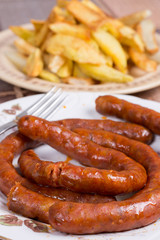 Raw domestic red sausages with fried potatoes