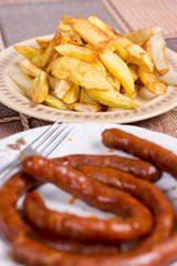 Raw domestic red sausages with fried potatoes