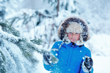 Fototapeta premium Cute little boy wearing warm clothes playing on winter forest