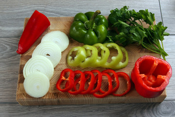 sliced onion and pepper on a kitchen Board with parsley