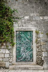 A green door in a stone building which is typical of scenes in old towns in Croatia.