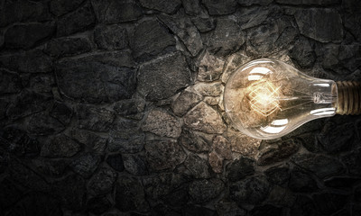 Light bulb on brick surface . Mixed media