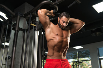 Fototapeta na wymiar Bodybuilder Exercising Triceps On Machine