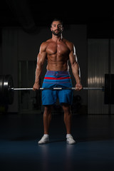 Fototapeta na wymiar Bodybuilder Performing Back Exercising With Barbell In Gym