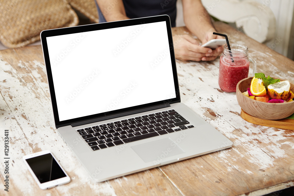 Poster generic modern laptop with blank copy space screen resting on wooden table with mobile phone, smooth