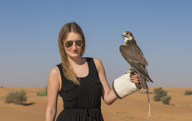 young woman with a saker falcon (falco churrug) in a desert near Dubai