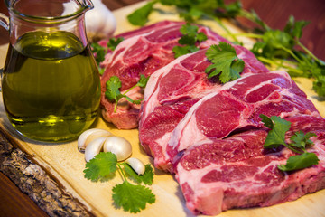 Fresh meat steak slices on wooden cut board with rosemary, salt and garlic. Background old wood.