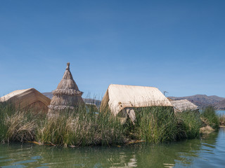 View of the Uros floating reed islands with boats, mysterious Lake Titicaca, Puno Region, Peru
