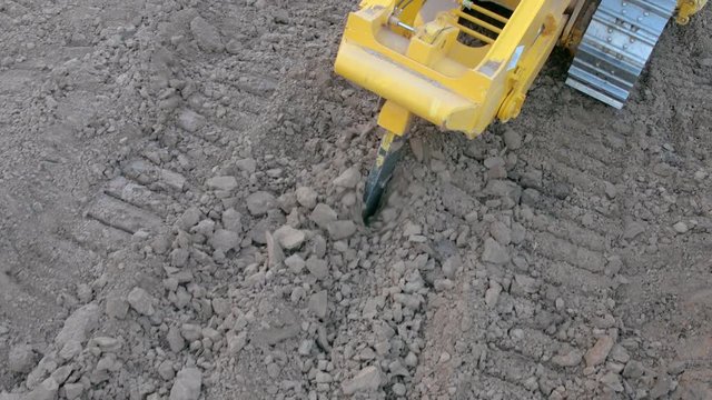Bulldozer with ripper shank penetrate and loosen the soil on construction site