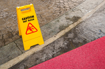 Yellow Wet Floor in rain season with red carpet.