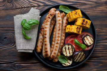 Grilled sausages, sweetcorn and aubergines in a frying pan