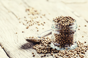 Coriander seed in a glass jar, vintage wooden background, select