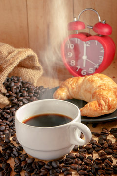 Hot coffee cup and red clock mark on 6 o'clock on wooden background in the morning