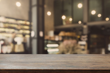 Wood table top and blurred restaurant interior background with vintage filter - can used for display or montage your products.
