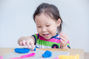 Little asian girl playing with dough on table