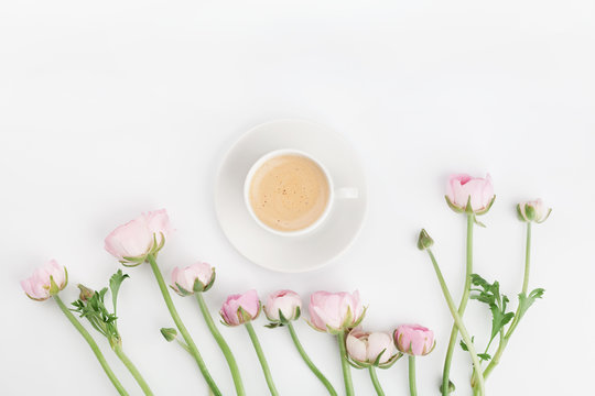 Beautiful spring Ranunculus flowers and cup of coffee on white table from above. Greeting card. Breakfast. Pastel color. Clean space for text. Flat lay style.