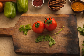 Tomatoes for cooking healthy vegeterian food on the board at the table in the kitchen.
