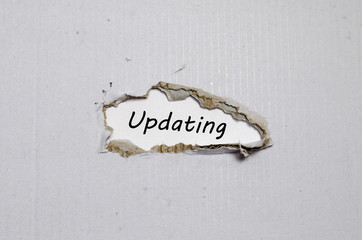 The word updating appearing behind torn paper