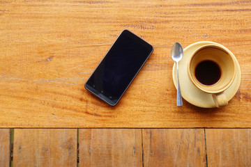 Smart phone and blank coffee mug with coffee stains stuck , after drinking it on the wooden table