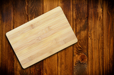 Empty bamboo cutting board on a old wooden table for product display.Top view
