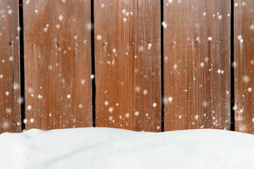 Falling snow on a background of an blurred old wooden barn wall