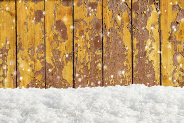 Falling snow on a background of an blurred old wooden barn wall