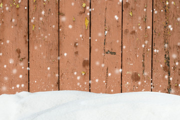 Falling snow on a background of an blurred old wooden barn wall