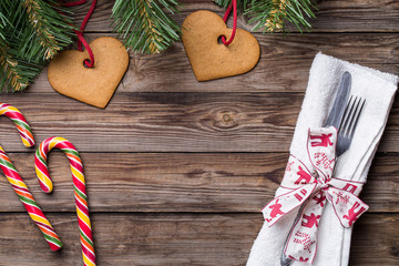 Christmas table place setting with fork and knife,decorated ribbon and bow, christmas pine branches, cookies and lollipop.