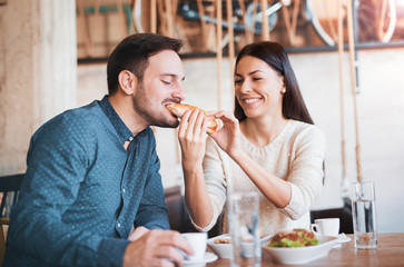 Beautiful young couple sitting in a cafe, having breakfast