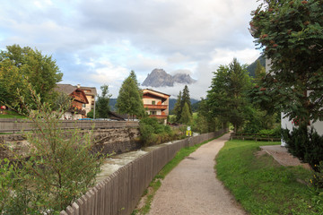 Fototapeta na wymiar Dolomites mountain Sextner Rotwand with clouds and footpath in village Sexten in South Tyrol, Italy