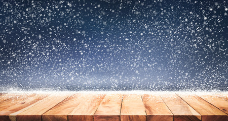 Empty wood table top with snowfall in night winter season background