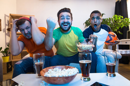Picture of excited and amazed friends watching football game on TV. Handsome men screaming when someone kicking goal.