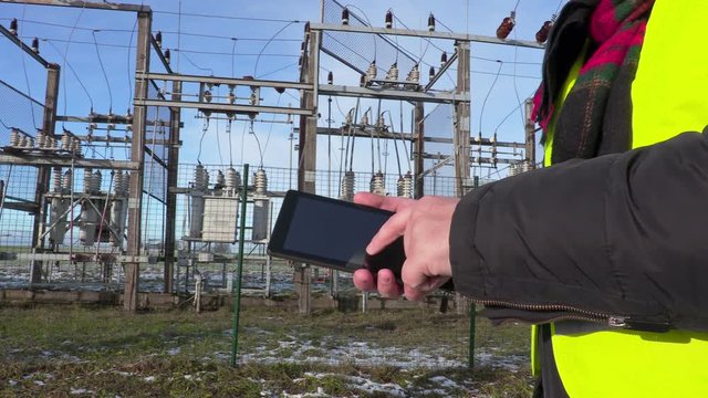 Electrician engineer using tablet near substation close up