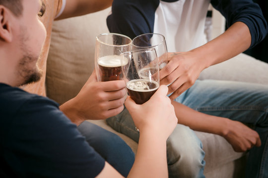 Image of friends drinking beer at home while sitting on sofa or couch. People spending weekends all together. Football match concept.