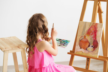 Portrait of a lovely little girl painting a picture in a studio