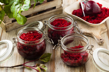 Grated beetroot marinated in jars. Wooden background.