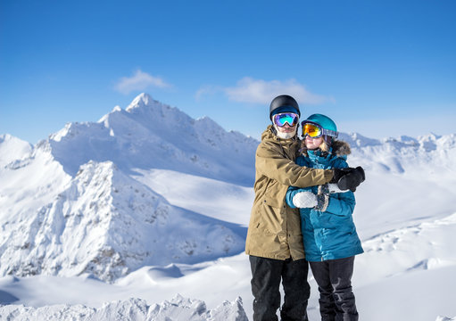 Happy couple snowboarders in mountains