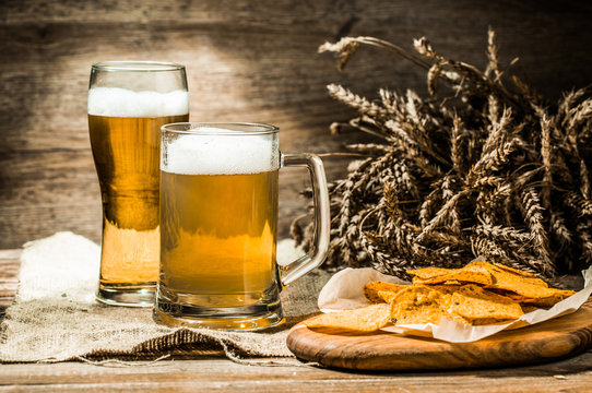 Mug, glass of beer with wheat spikelets and potato chips