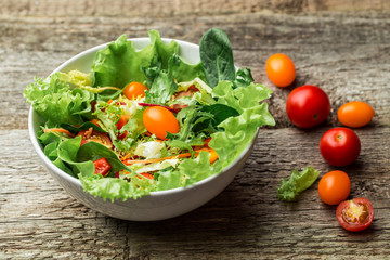 Salad with fresh vegetables - tomatoes, carrots, bell peppers and mixed greens - arugula, mesclun, mache.