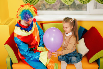 Obraz na płótnie Canvas Amusing clown give air balloon to the little girl