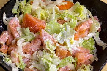 Fresh vegetable salad with white sauce is in a ceramic plate.