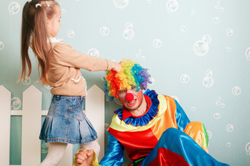 Little girl pulls clown hair.