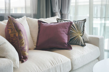 Beautiful purple and green pillows on white sofa in living room