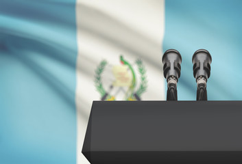 Pulpit and two microphones with a national flag on background - Guatemala